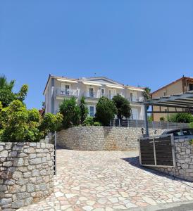 a large white house behind a stone wall at Louis' apartment with view in Gythio