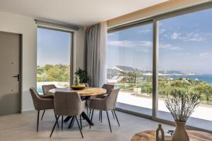 a dining room with a table and chairs and a large window at Melody Blue Villa in Argassi