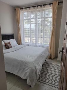 a bedroom with a bed and a large window at 1 Bedroom Apartment near UN GIGIRI and US Embassy Village Market in Nairobi