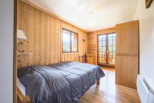 Un dormitorio con una cama en una pared de madera. en Pré-vernay 7pers, en Saint-Jean-dʼArves