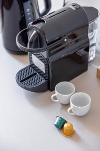 ein schwarzer Toaster mit zwei Tassen auf einem Tisch in der Unterkunft Vatican Pertusa Luxury Suites by Quinto Piano in Rom