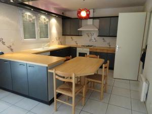 une cuisine avec une table en bois et des armoires bleues dans l'établissement CARCANS MAUBUISSON LOCATION SAISONNIERE VILLA 6 couchages, à Carcans 2 autres photos