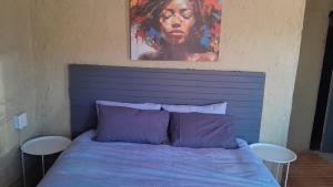 a bed with a blue headboard with a painting above it at Comfy at Sosha in Soshanguve