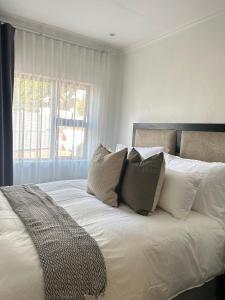 a bedroom with a bed with pillows and a window at Elyon Suites in Kempton Park