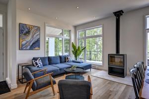 a living room with a blue couch and a fireplace at Kensho Enjoy nature life with Hot tub in Sainte Béatrix