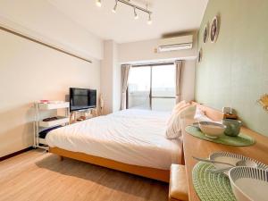 a bedroom with a bed and a table and a tv at Direct 6min to Nagoya Sta Max4ppl 1BDR Wi-Fi in Aoichō