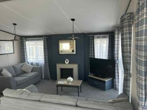 a living room with a couch and a tv at Parkview holiday lodge in Lossiemouth