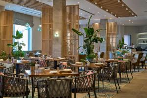 a restaurant with wooden tables and chairs and plants at The Chedi Luštica Bay in Tivat