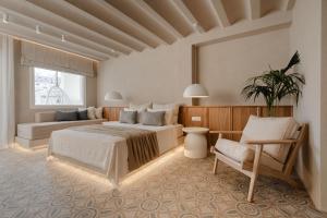 a large bedroom with two beds and a chair at Castellum Suites in Naxos Chora