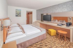 a hotel room with a bed and a flat screen tv at Lotus Therme Hotel & Spa in Hévíz