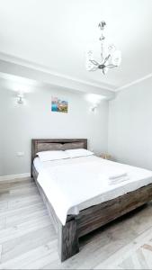 a bedroom with a wooden bed in a white room at Cozy Almaty Escape in Almaty
