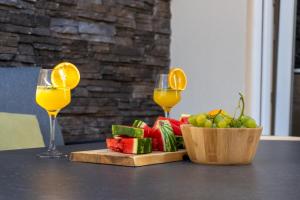 a table with two glasses of orange juice and a bowl of fruit at Vacation House Privlaka in Privlaka