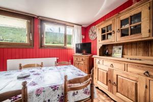 a dining room with a table and a tv and red walls at Appartement en residence in Morzine