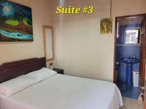 ein Schlafzimmer mit einem weißen Bett und ein Badezimmer in der Unterkunft Hostal Landivar - A media cuadra de la plaza in Buena Vista