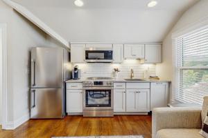 Una cocina con gabinetes blancos y un refrigerador de acero inoxidable. en The Livery on 5th, Unit B, en Nashville