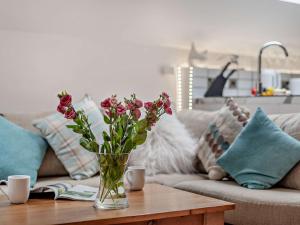 a vase of flowers on a table in front of a couch at 1 Bed in Eskdale 95105 in Eskdale