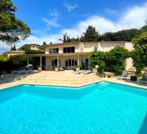 a large blue swimming pool in front of a house at Charming Villa with stunning sea views in Mougins