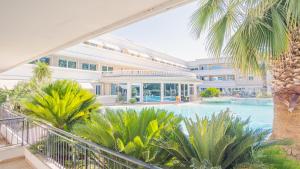 an indoor pool with palm trees in front of a building at Relais du Lac Village - Italian Homing in Desenzano del Garda