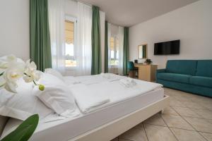 ein Schlafzimmer mit einem weißen Bett und einem blauen Sofa in der Unterkunft Hotel MAX Lazise &Appartamenti - A due Passi dai Parchi Più Famosi in Lazise