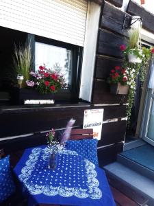 une table sur un porche avec des fleurs à une fenêtre dans l'établissement DAS LANDHAUS KLAMBAUER - APARTMENTHAUS Prämiumpartnerbetrieb St MartinsTherme, à Frauenkirchen