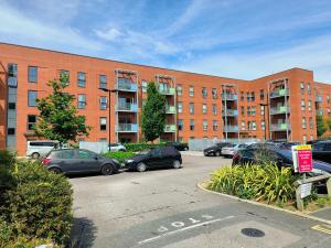 a parking lot with cars parked in front of a brick building at Issara Apartments 35 - Great Location & Private Parking in Portsmouth