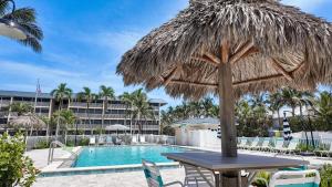 a table with a straw umbrella next to a swimming pool at Sanibel Siesta on the Beach in Sanibel