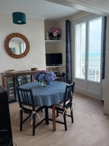 a dining room table with a vase of flowers on it at Le Grand Bleu in Saint-Valéry-en-Caux
