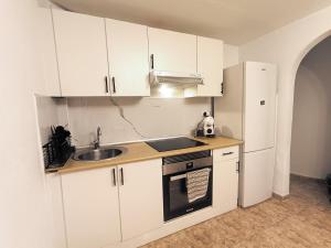 a kitchen with white cabinets and a sink and a refrigerator at Bellavista Basement in Costa Del Silencio
