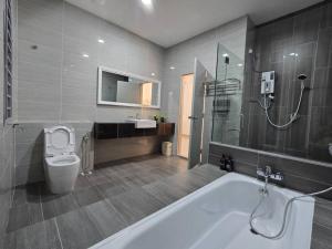 a bathroom with a tub and a toilet and a sink at TropINN LoDonHeartBeat 5LuxRoom CirPool BBQ & KTVFun in Bandar Penawar +28 photos
