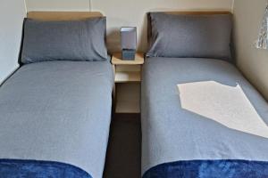 two beds next to each other with a night stand at Golden Sands 3-Bed Caravan Parking & Pet Friendly in Rhyl