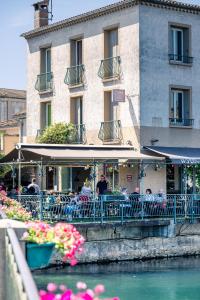 a group of people sitting at a restaurant next to the water at Le Bassin Hôtel Restaurant in LʼIsle-sur-la-Sorgue