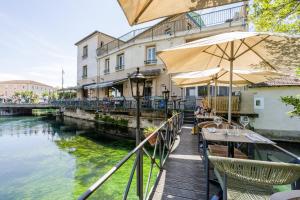 a table with an umbrella next to a river at Le Bassin Hôtel Restaurant in L'Isle-sur-la-Sorgue