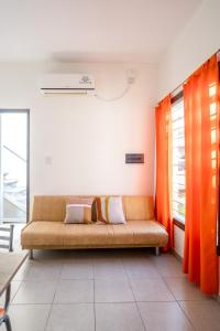 a couch in a living room with orange curtains at Departamentos Brown in San Rafael
