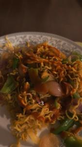 a plate of food with noodles and vegetables on it at Surya hills view in Jāmb