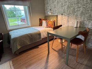 a bedroom with a bed and a table and a window at Lantligt läge nära golfbana in Västerås