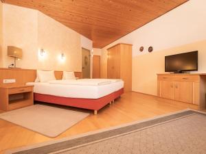 a large bedroom with a bed and a television at Macher's Landhotel in Sankt Jakob in Defereggen +47 photos