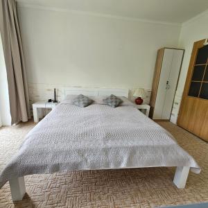 a white bed in a white bedroom with two tables at Apartman Tatranská Štrba in Štrba +24 photos