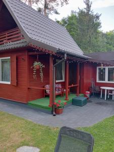 a red cabin with a patio and a table at Domek Pod Sosnami D in Krasnobród