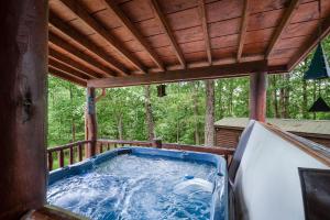 einen Whirlpool auf der hinteren Veranda einer Hütte in der Unterkunft Whippoorwill Calling - Panoramic Mineral Bluff Cabin - Panoramic Views, Hot Tub, Nature Trail, Private Cul-De-Sac Home, Firepit, in Mineral Bluff