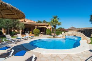 einen Pool in einem Garten mit Stühlen und einem Sonnenschirm in der Unterkunft Can Revell - Villa en el paraíso in Sant Llorenç des Cardassar