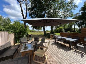 una terrazza in legno con tavolo e ombrellone di Maison vu Lac en première ligne du lac de Lacanau avec terrain de tennis privatif a Lacanau