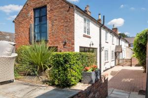 a brick house with bushes in front of it at Marsh Mallow Cottage - Hot Tub Packages Available in Loughborough