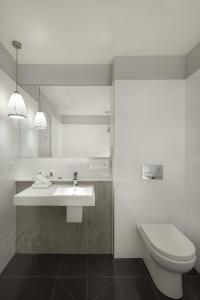 a white bathroom with a toilet and a sink at Mercure Warragul in Warragul