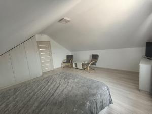 a attic bedroom with a bed and two chairs at Colț de lavandă in Braşov