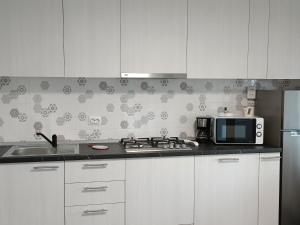 a kitchen with white cabinets and a microwave and a sink at Colț de lavandă in Braşov