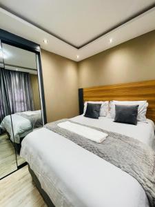 a bedroom with two beds and a large mirror at Que Self Catering Apartments in Gaborone