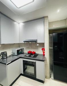 a kitchen with white cabinets and a stove top oven at Que Self Catering Apartments in Gaborone