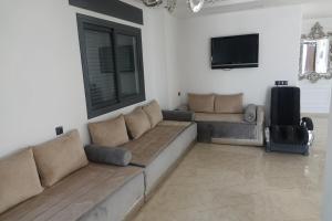 a living room with a couch and a flat screen tv at Chambre double privée, Surf Camp Achakkar in Tangier