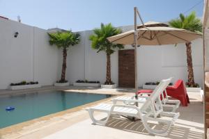 a pool with a chair and an umbrella next to a pool at Chambre double privée, Surf Camp Achakkar in Tangier