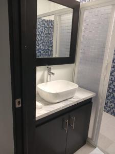 ein Badezimmer mit einem weißen Waschbecken und einem Spiegel in der Unterkunft Casa Garcia - Alberca privada in Tequesquitengo